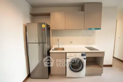 Modern kitchen with sleek appliances including fridge and washing machine, perfect for urban living.