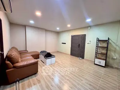 Spacious living room with modern leather sofa and sleek tile flooring, perfect for relaxation and entertainment.