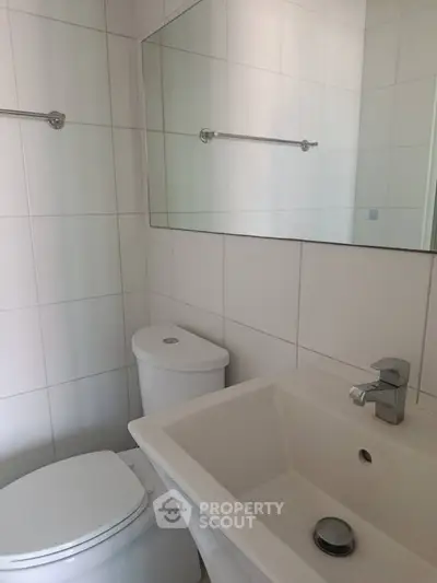 Modern bathroom with sleek white fixtures and large mirror