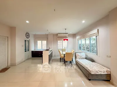 Spacious open-plan living area with modern kitchen and dining space, featuring large windows and elegant decor.