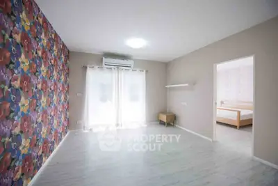 Spacious bedroom with floral accent wall and natural light