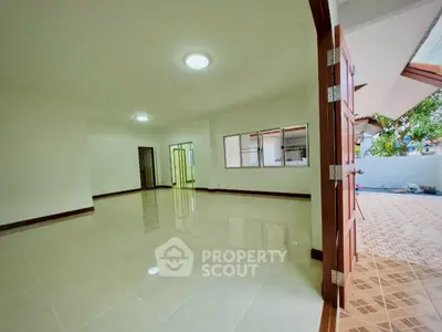 Spacious open-plan living area with tiled floors and ample natural light.