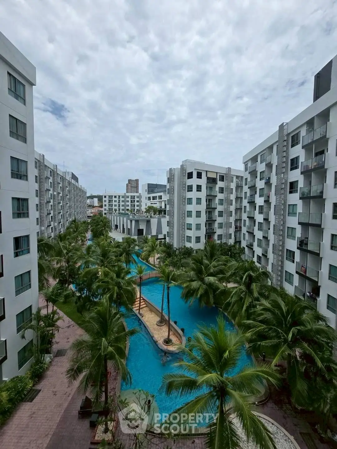 Luxurious residential complex with stunning pool and lush greenery, offering a serene urban oasis.
