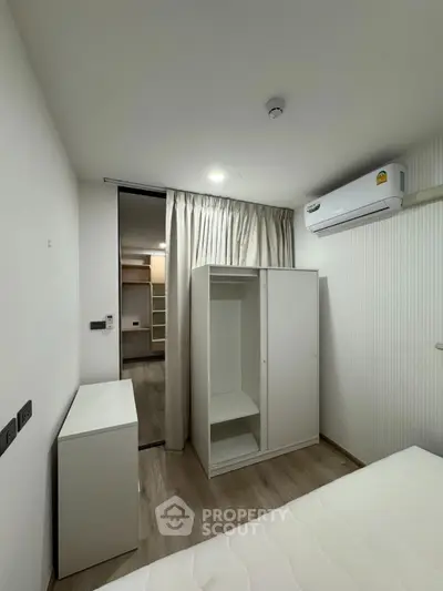 Modern bedroom with sleek white furniture and built-in air conditioning