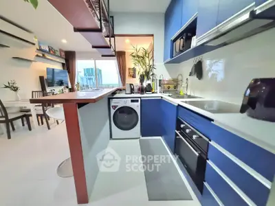 Modern kitchen with blue cabinets, washing machine, and open layout in stylish apartment.
