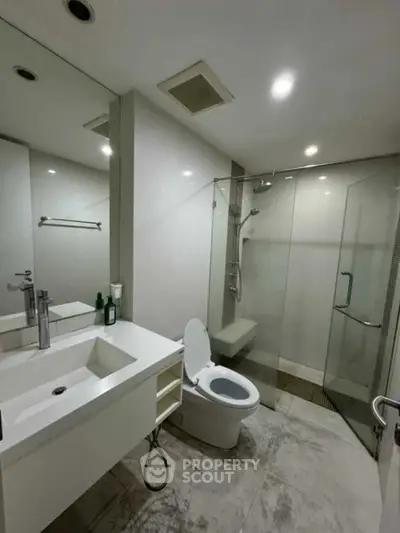 Modern bathroom with glass shower and sleek vanity in contemporary apartment.