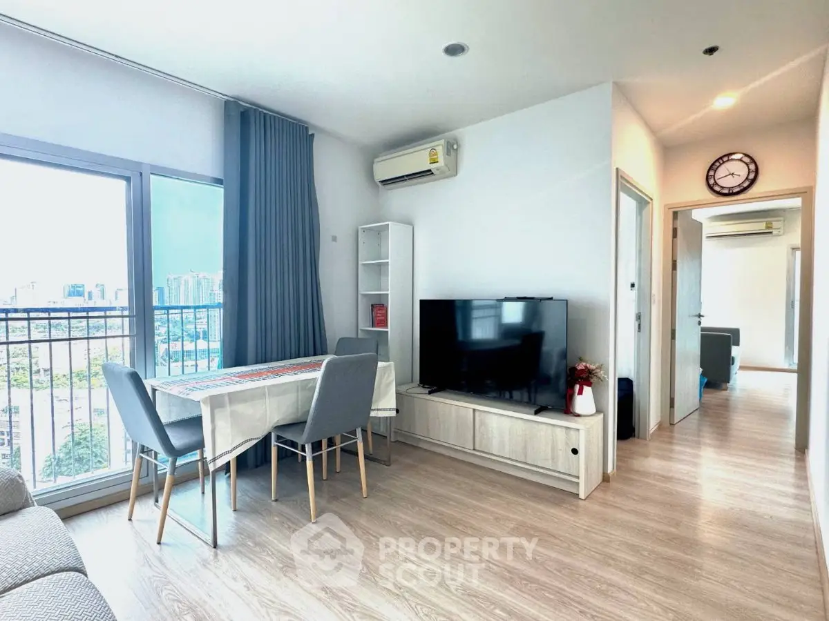Modern living room with city view, featuring sleek furniture and natural light.