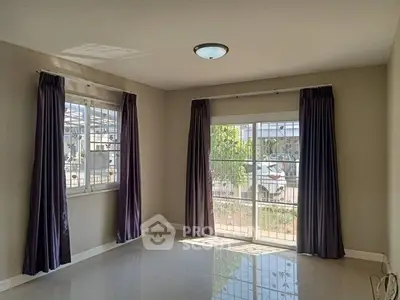 Bright living room with large windows and purple curtains, offering ample natural light.