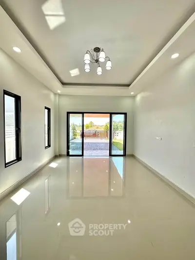 Spacious living room with large windows and balcony access, offering abundant natural light and modern design.