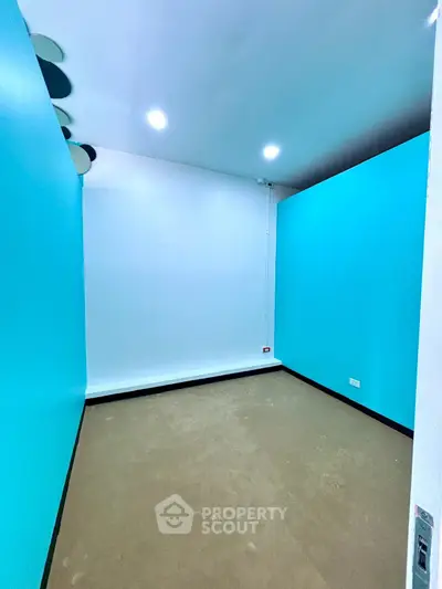 Spacious empty room with vibrant blue walls and modern lighting