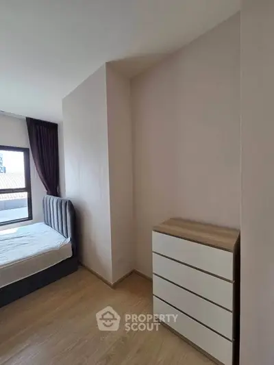 Modern bedroom with stylish bed and sleek dresser, featuring natural light and wooden flooring.