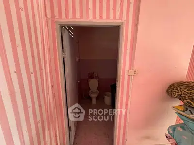 Charming pink-themed bathroom with striped wallpaper and cozy decor.