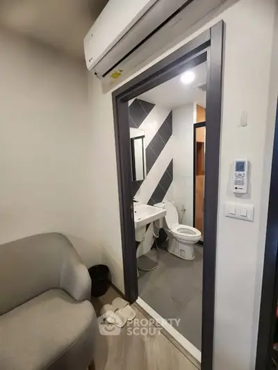 Compact bathroom with modern fixtures and adjacent cozy seating area.