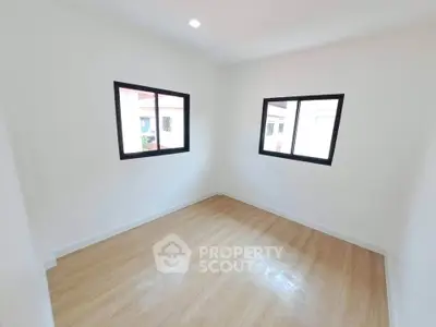 Bright and airy empty room with wooden flooring and large windows, perfect for customization.