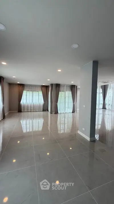 Spacious modern living room with large windows and elegant curtains, perfect for natural light and open living.