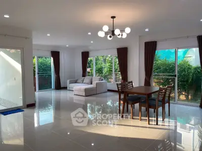 Spacious living room with modern furniture and large windows offering garden views.