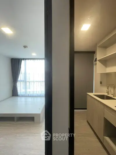 Modern apartment interior with open kitchen and spacious living area, featuring large windows and sleek design.