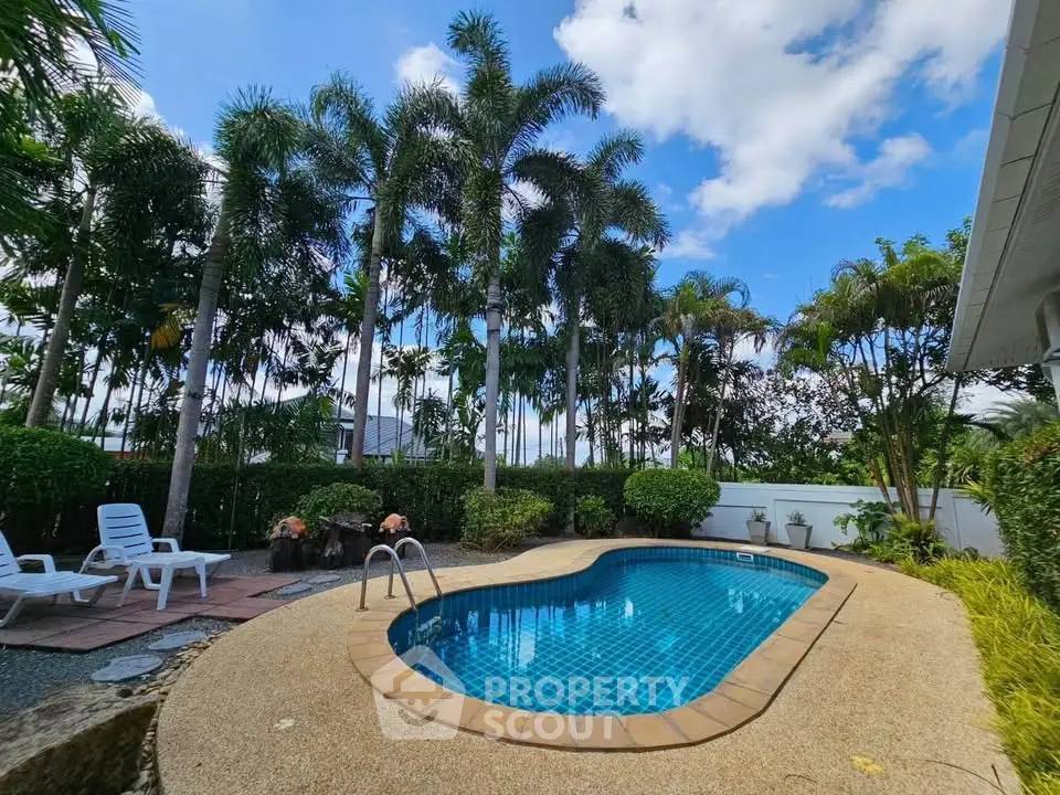 Stunning backyard pool oasis with lush palm trees and clear blue sky.