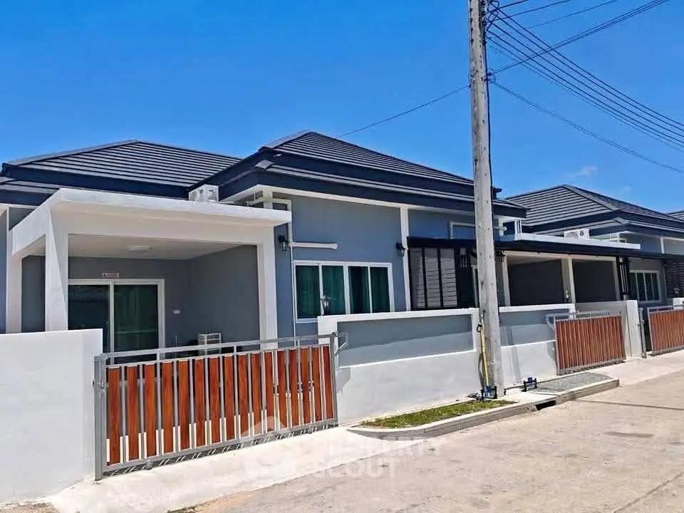 Modern single-story homes with sleek design and gated entrance in a sunny neighborhood.
