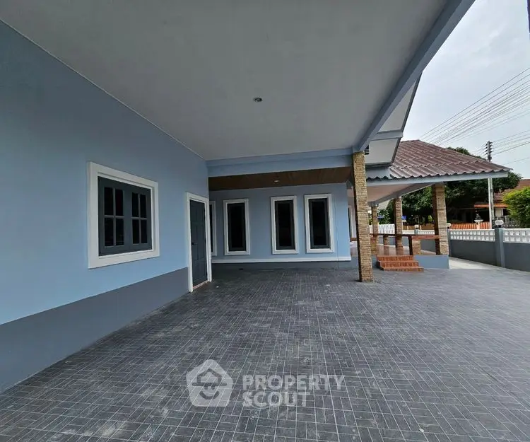 Spacious modern home exterior with covered patio and tiled driveway.