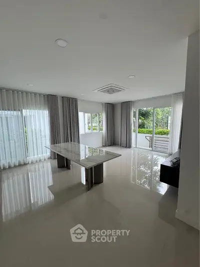 Spacious modern living room with large windows and elegant curtains, perfect for natural light lovers.