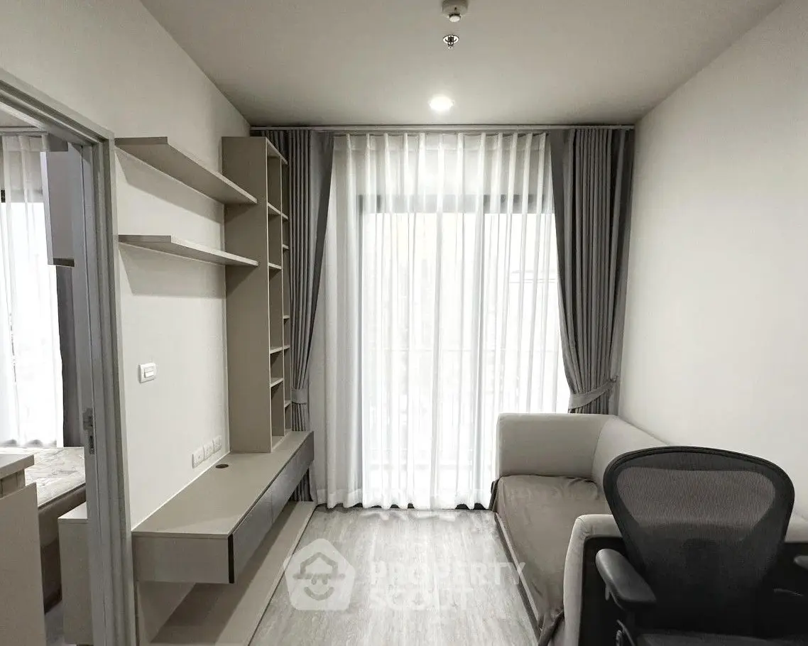 Modern living room with sleek furniture and large window draped with elegant curtains.