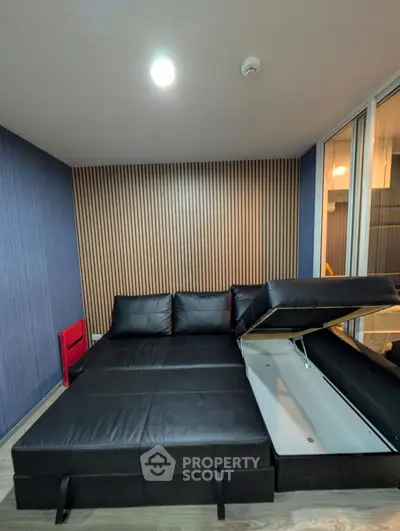 Modern living room with sleek black leather sectional sofa and stylish wood paneling.