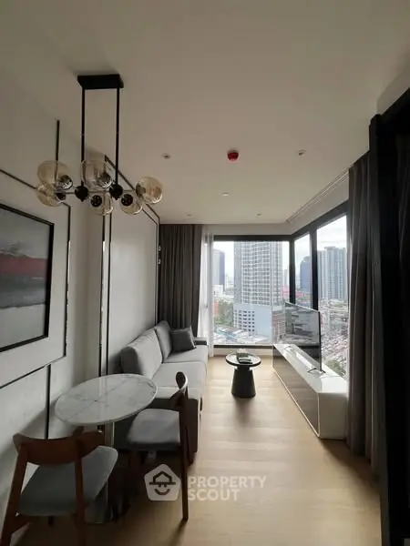Modern living room with city view, stylish furniture, and large windows in a high-rise apartment.
