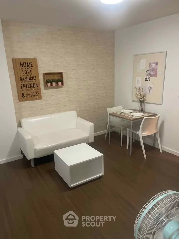 Cozy living room with white sofa and dining table, perfect for small gatherings.