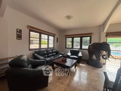 Spacious living room with leather sofas and unique elephant sculpture, offering a cozy and artistic ambiance.
