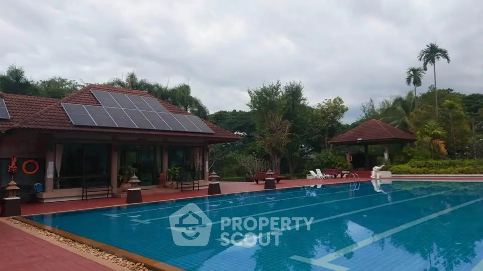 Luxurious villa with solar panels and a stunning outdoor pool surrounded by lush greenery.