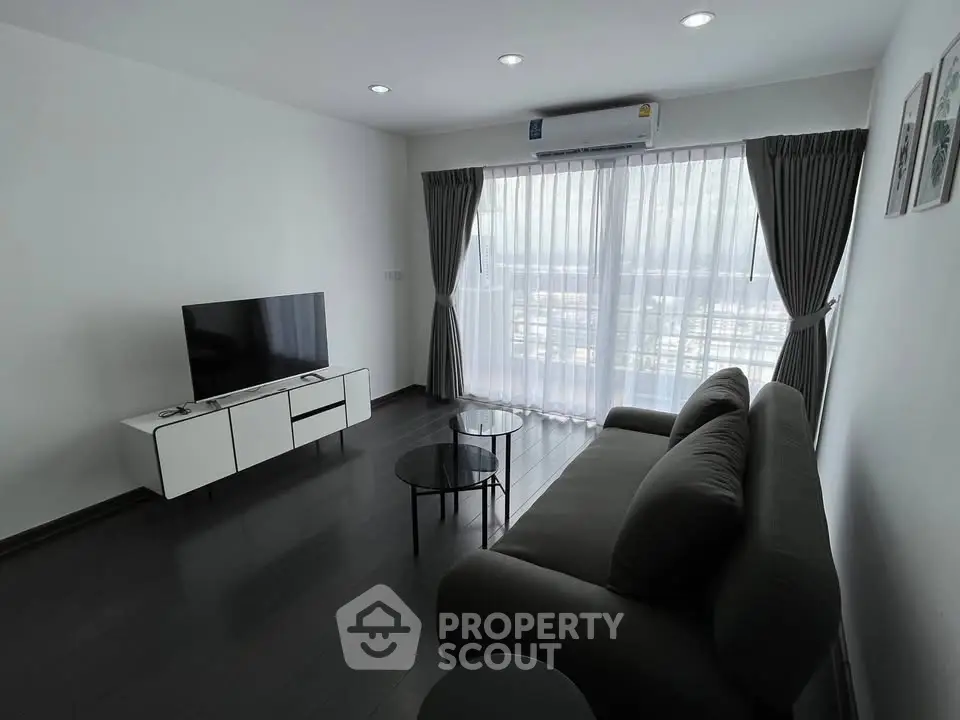 Modern living room with sleek furniture and large window offering natural light.