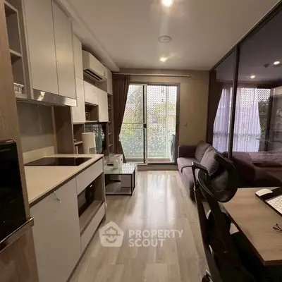 Modern studio apartment with open layout and balcony access, featuring sleek kitchen and cozy living area.