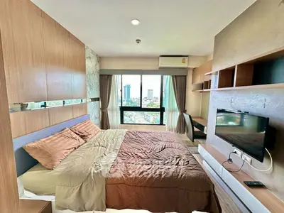 Modern bedroom with city view, featuring cozy bed and wall-mounted TV.