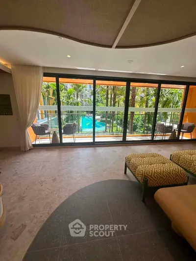 Luxurious living room with floor-to-ceiling windows overlooking a tropical pool and garden.
