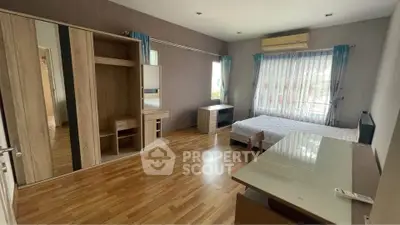 Spacious bedroom with wooden flooring and modern furniture