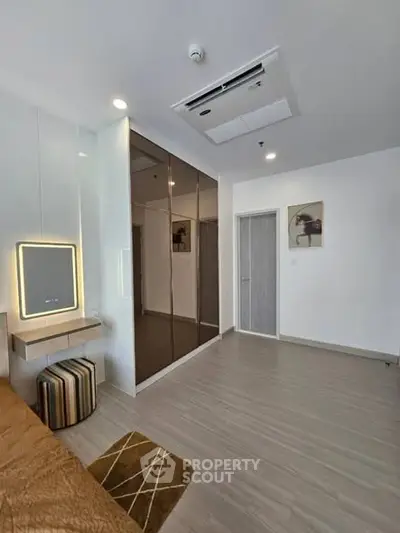 Modern bedroom with stylish decor and mirrored wardrobe