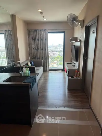 Modern living room with balcony view, sleek furnishings, and open layout in urban apartment.