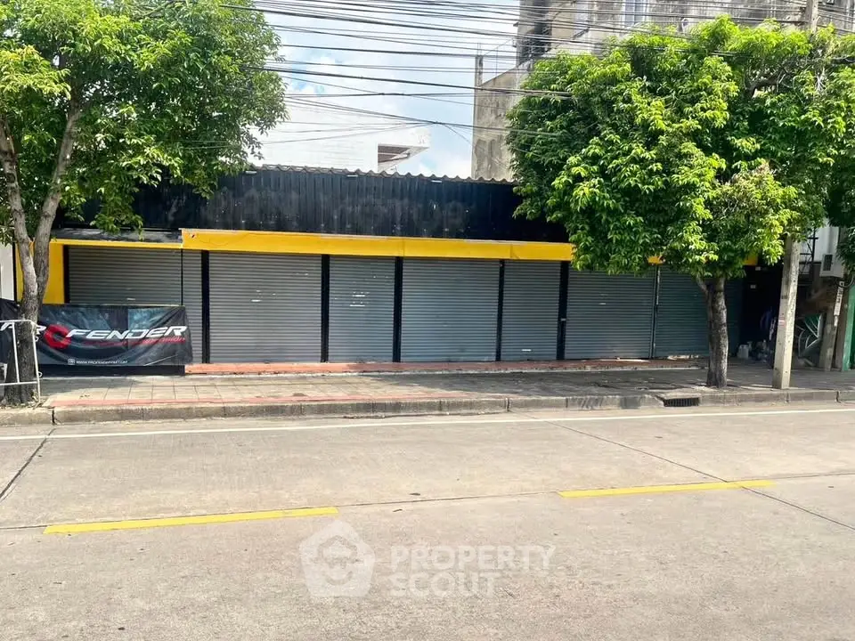 Commercial property with closed shutters and trees on a sunny street