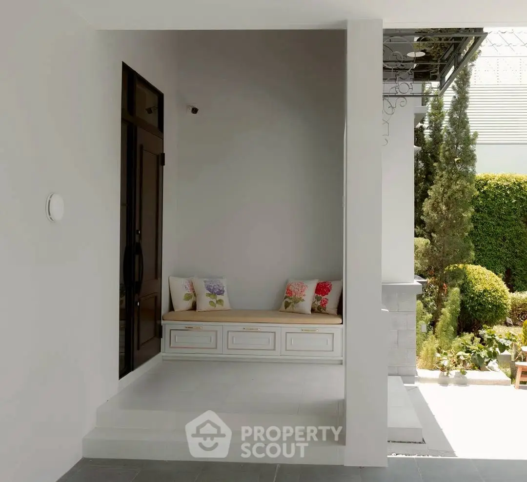 Charming entrance with cozy seating and lush garden view, perfect for relaxation and welcoming guests.