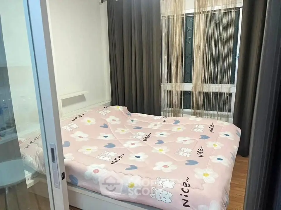 Cozy bedroom with floral bedding and large window, perfect for relaxation.
