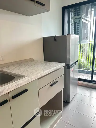 Modern kitchen with marble countertop and stainless steel fridge in a bright apartment.