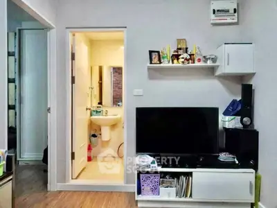 Modern living room with TV unit and view into a compact bathroom, showcasing efficient space utilization.