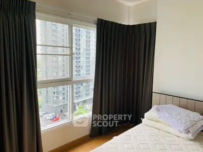 Cozy bedroom with large window offering stunning urban views in modern apartment.