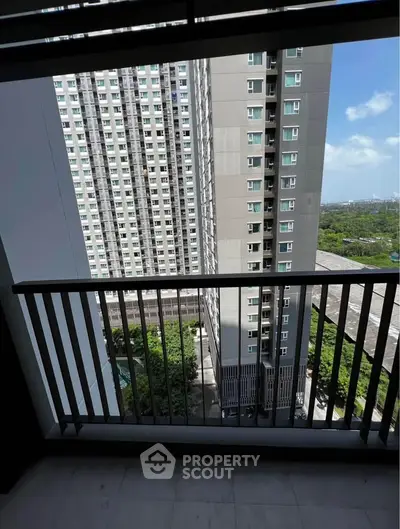 Stunning high-rise balcony view overlooking modern cityscape and lush greenery.