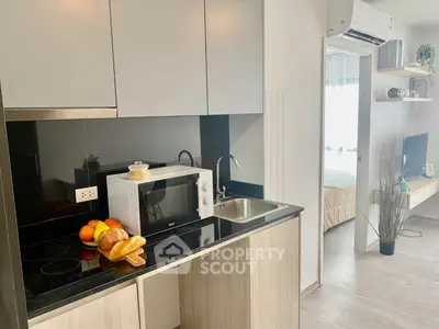 Modern kitchen with sleek cabinetry and appliances, adjacent to a cozy bedroom, ideal for urban living.