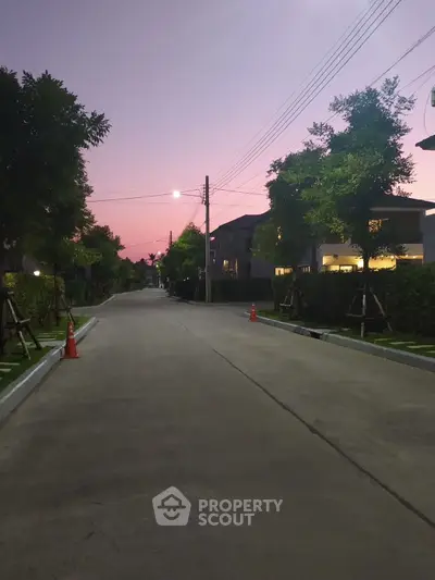 Charming suburban street view at dusk with modern homes and lush greenery.
