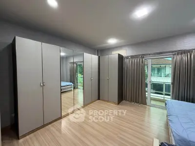 Spacious bedroom with mirrored wardrobes and large windows offering natural light and a view.