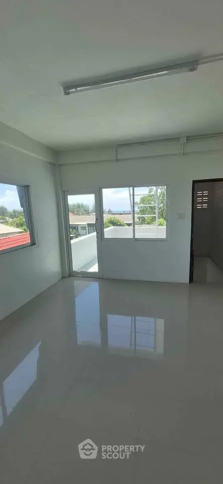 Bright living room with large windows and balcony access, offering a serene view.