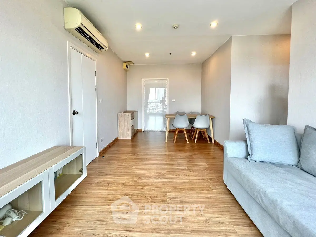 Spacious living room with modern decor and wooden flooring, featuring a cozy sofa and dining area.